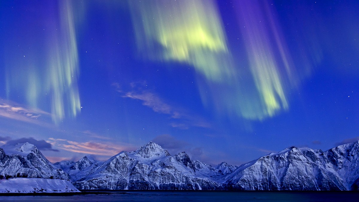 A view of the Northern Lights over snowy mountains
